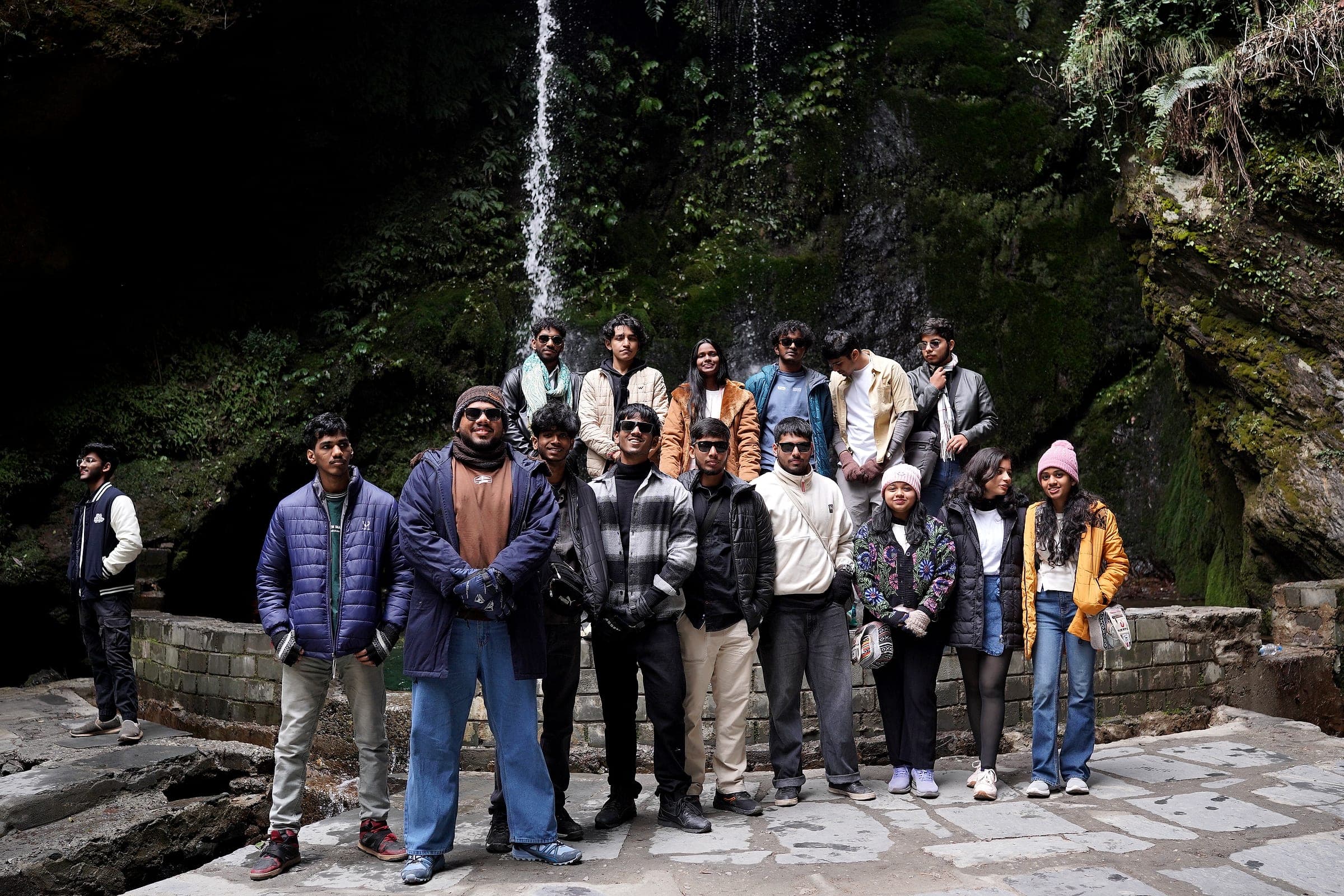 A trip captain and their group gathered at a waterfall in Himachal Pradesh