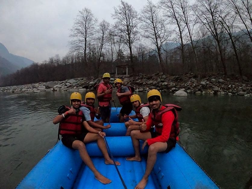 Students in helmets and life jackets on a raft at Rishikesh